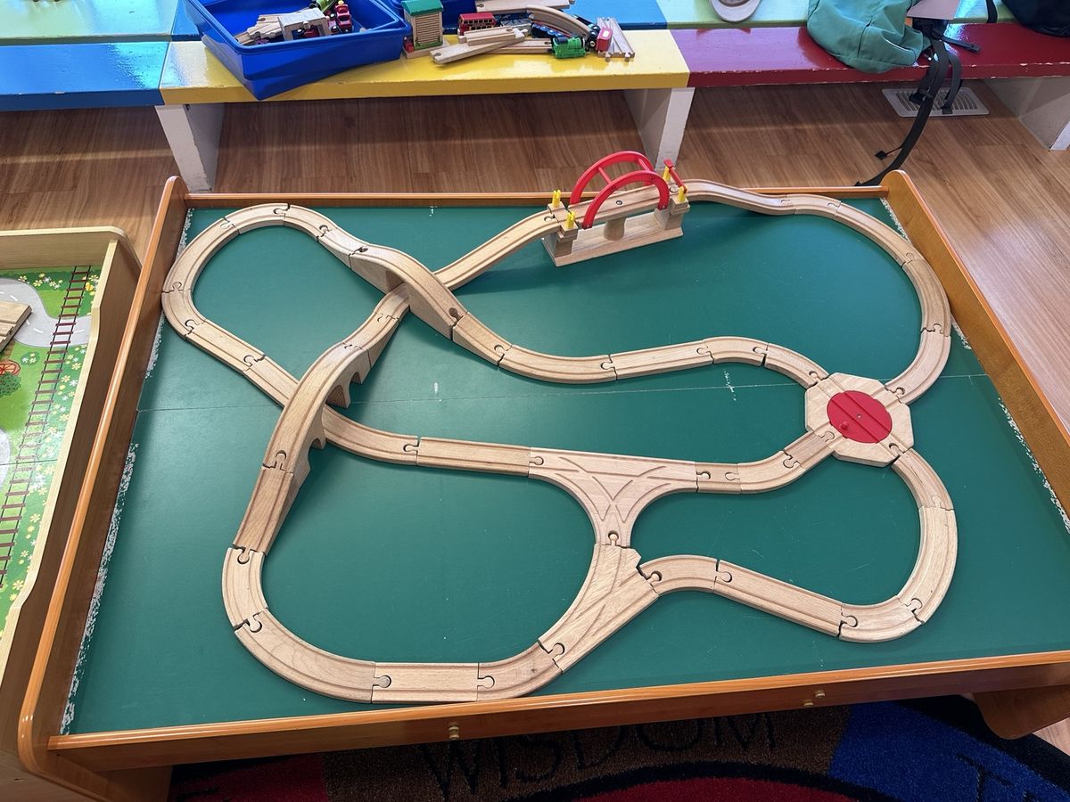 A wooden train track laid out on an activity table.