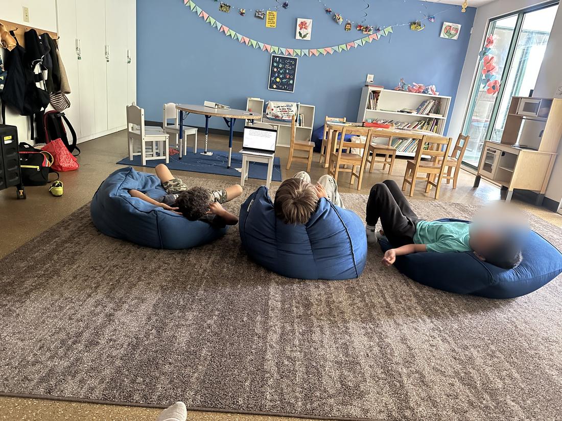 Three children relaxing on bean bags during a group activity.
