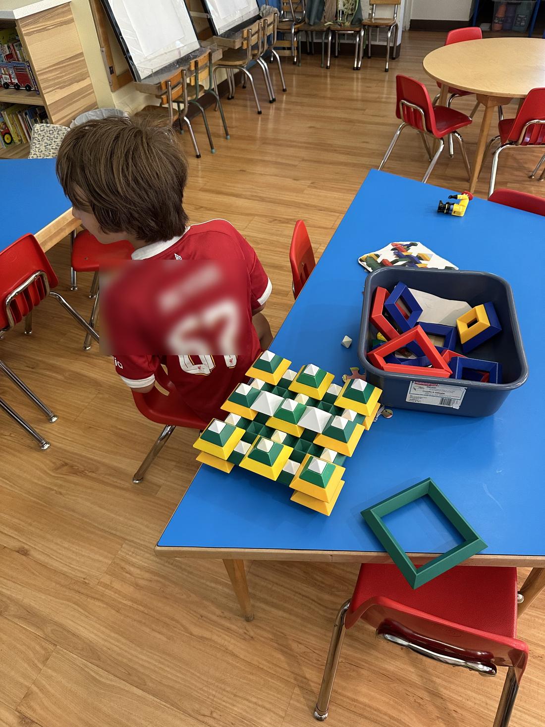 A child building a pattern with coloured blocks at a table.